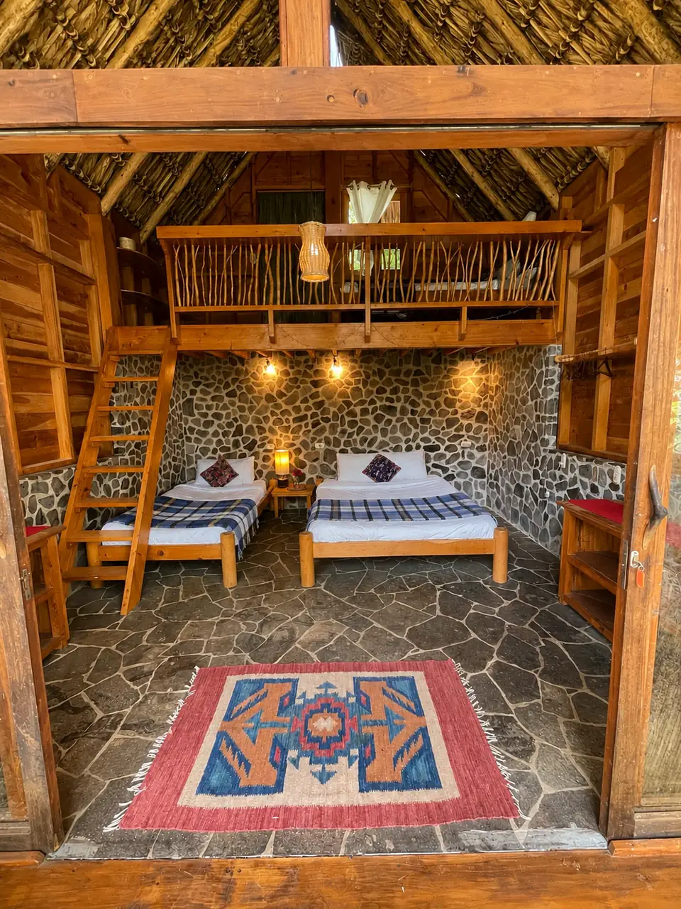 Inti: ground floor from the doorway: two beds, loft above, rug.