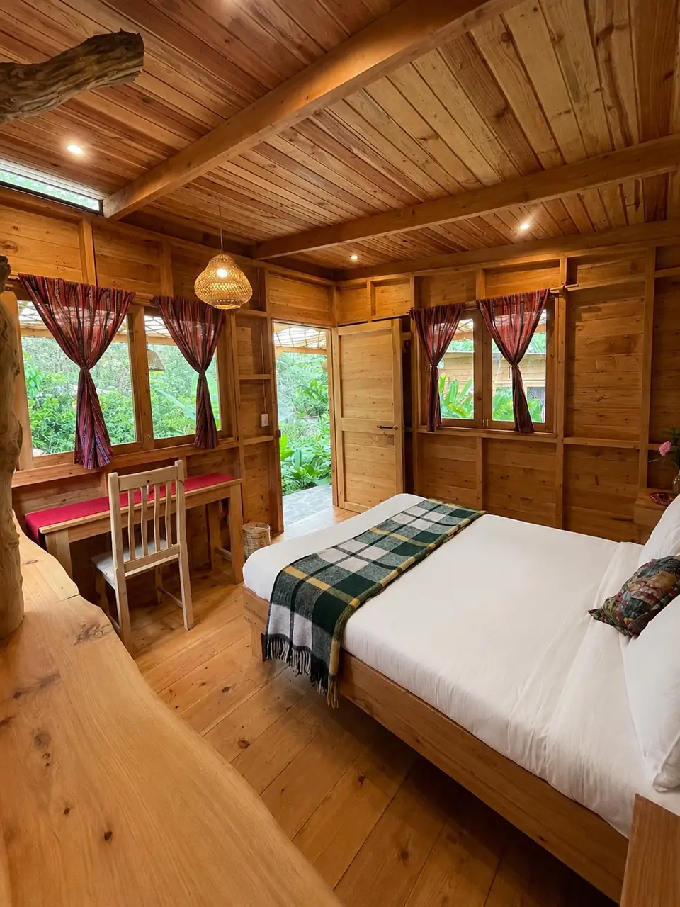 Garden Cabin: queen bed, desk and door, red curtains.