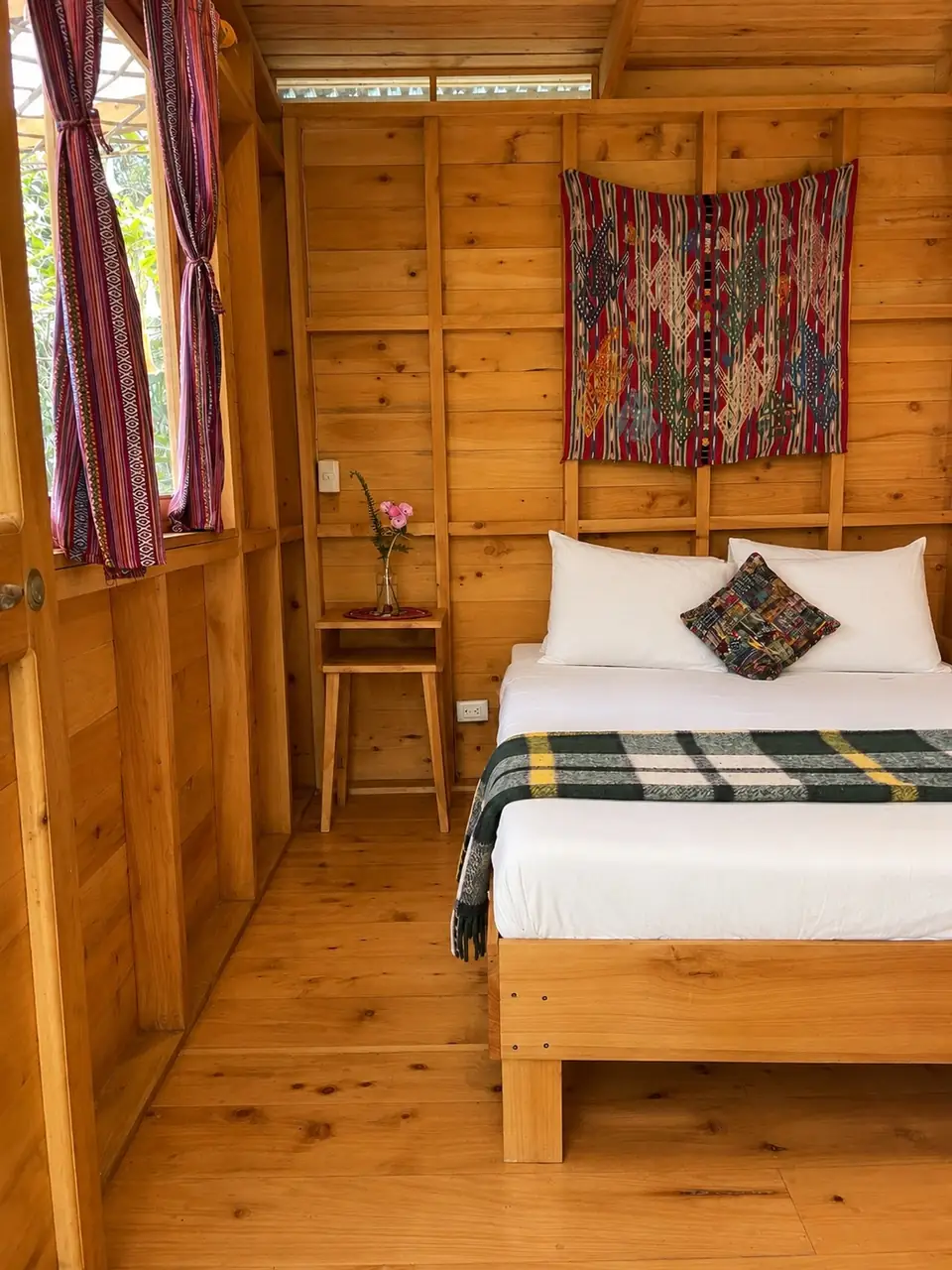 Garden Cabin: bed corner with wall hanging.
