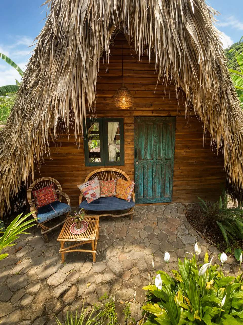 Inti: exterior: thatched A-frame with blue door and patio chairs.