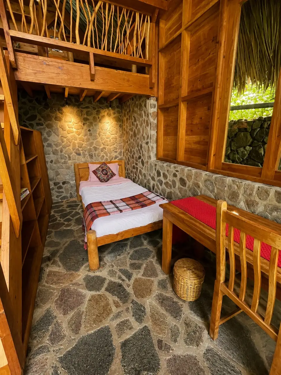 Kiya: ground floor: single bed, desk and stone wall.