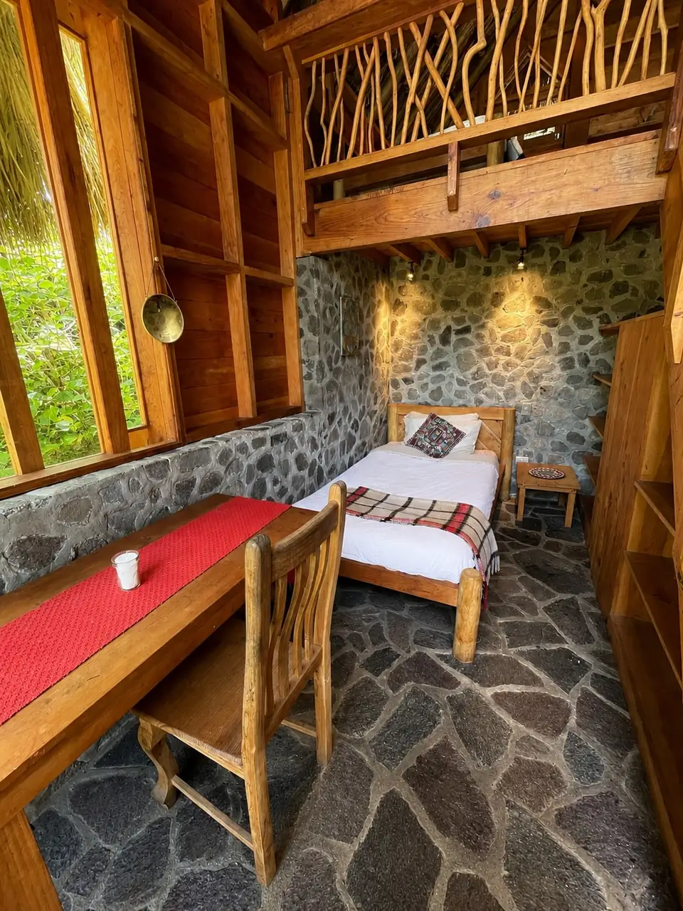 Kiya: desk and bed by the stone wall.
