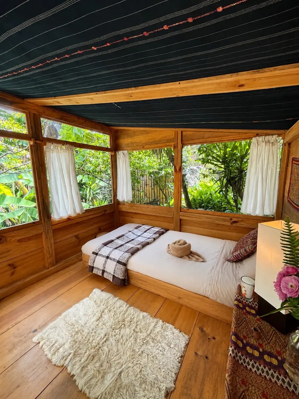 Tambo: single bed with rug, screened windows.